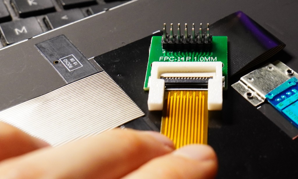 A 12-pin TrackPoint FFC being inserted into a 14-pin breakout through a 3D-printed U-shaped guide.